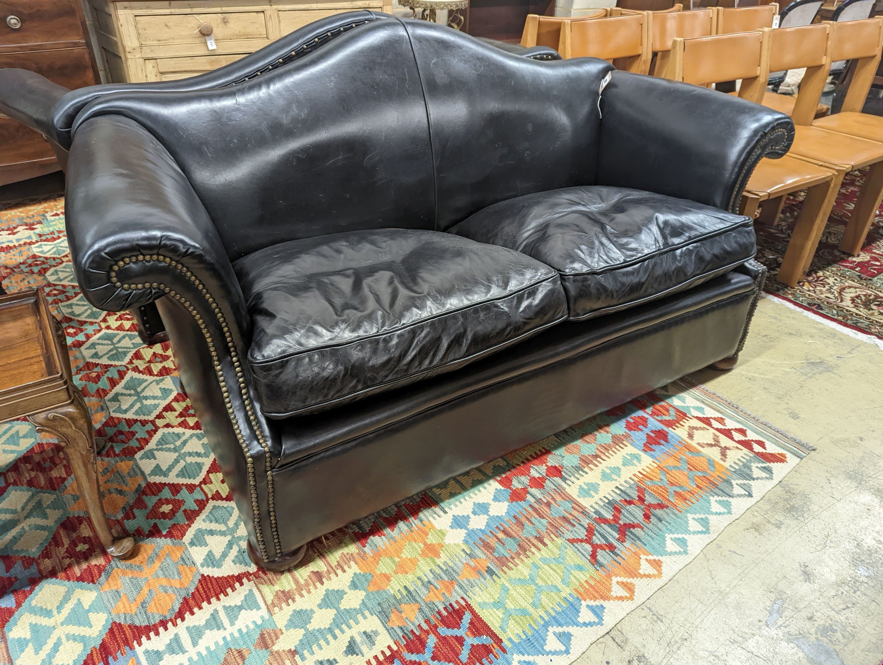 A pair of black leather scroll arm two seater settees on flat bun feet, length 184cm, depth 80cm, height 93cm